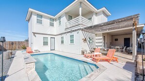 A two-story house with a swimming pool, outdoor furniture, and a covered patio area. - La Dolce Vida by Silver Sands Vacation Rentals (Port Aransas)