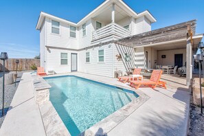 A two-story house with a swimming pool, outdoor furniture, and a covered patio area. - La Dolce Vida by Silver Sands Vacation Rentals (Port Aransas)