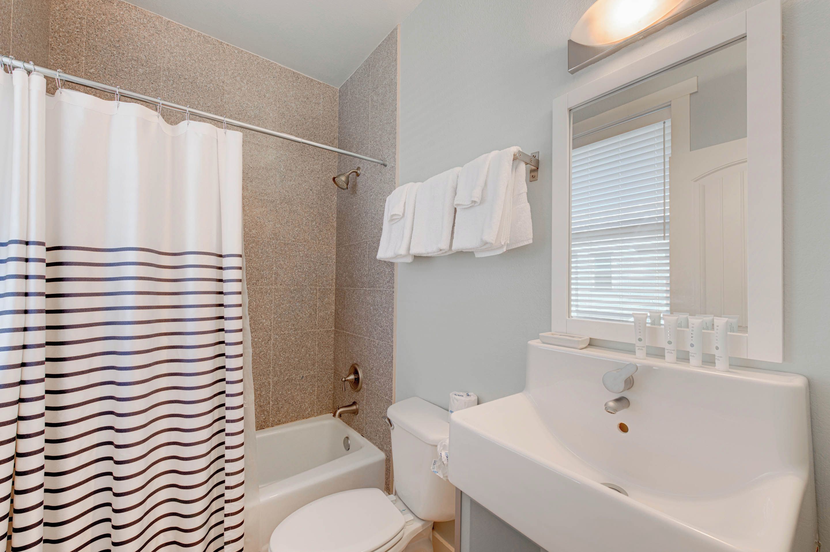 Une salle de bain équipée d’un rideau de douche, d’une baignoire, de toilettes et d’un lavabo avec des articles de toilette.