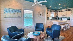 A modern kitchen with white cabinets, a microwave, and a coffee maker. There is a dining area with blue chairs and a wooden table. - Jumpin' Jellyfish by Silver Sands Vacation Rentals (Port Aransas)