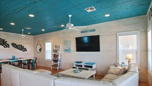 A living room with a white sofa, a coffee table, a TV, and a ceiling fan. - Jumpin' Jellyfish by Silver Sands Vacation Rentals (Port Aransas)
