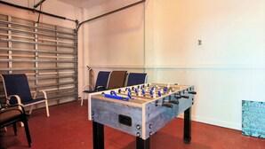 A foosball table in a room with chairs and a garage door. - Jumpin' Jellyfish by Silver Sands Vacation Rentals (Port Aransas)