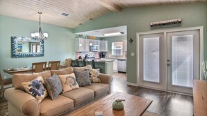 A living room with a beige sofa, wooden coffee table, and a chandelier. - Just Beachy by Silver Sands Vacation Rentals (Port Aransas)