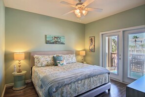 A bedroom with a bed, two bedside lamps, a ceiling fan, and artwork on the walls.