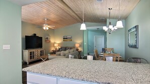 A kitchen with a granite countertop, wooden ceiling, and a dining area with chairs and a table. - Just Beachy by Silver Sands Vacation Rentals (Port Aransas)