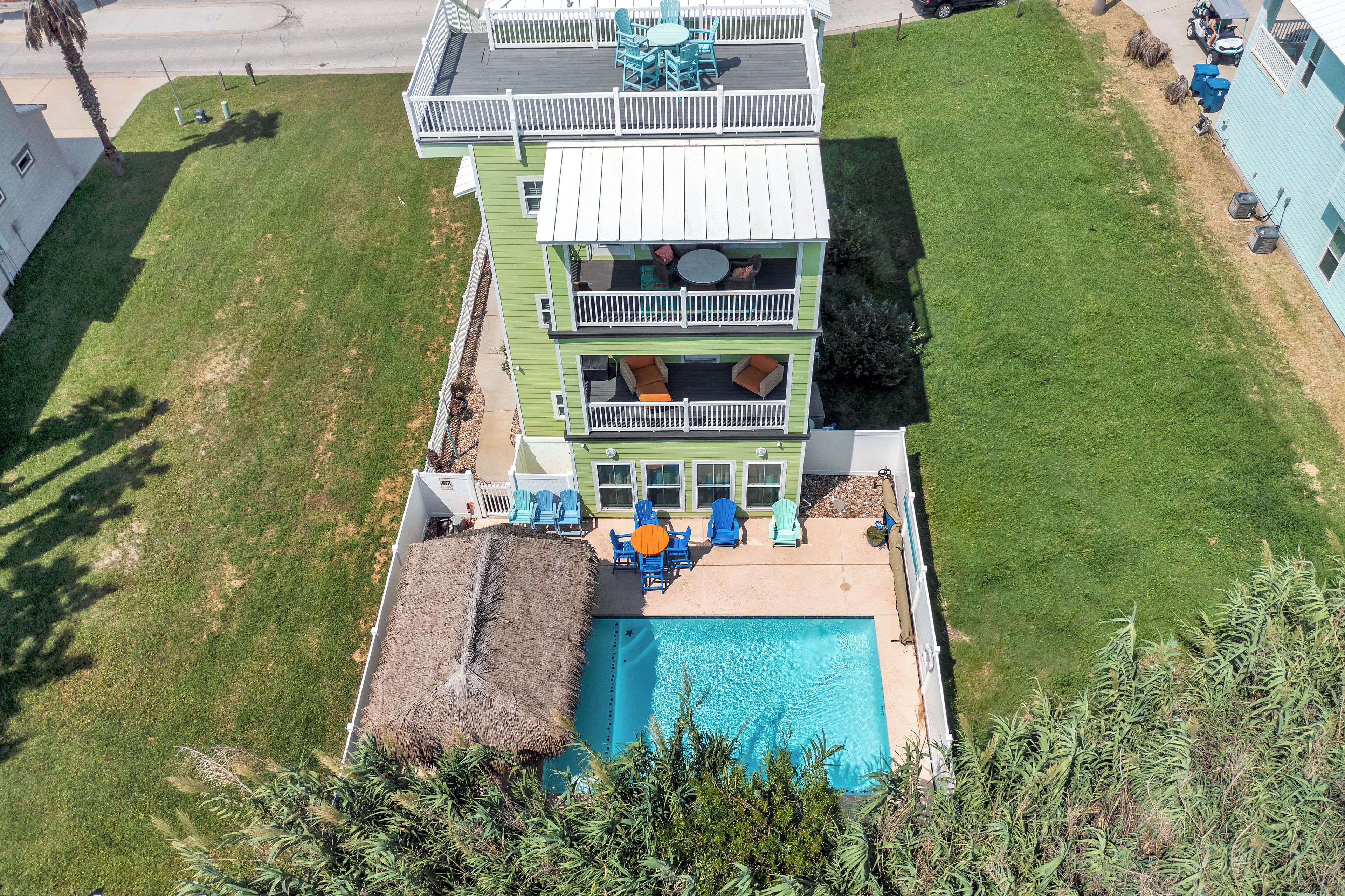 Un immeuble à plusieurs étages doté d’une piscine, d’un espace extérieur aménagé et d’une structure à toit de chaume.