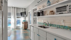 A modern kitchen with white cabinetry, a stainless steel sink, and a built-in oven. - Nauti Beach by Silver Sands Vacation Rentals (Port Aransas)