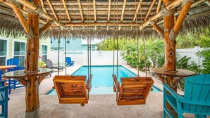 A wooden swing set over a pool with a thatched roof overhead. - Nauti Beach by Silver Sands Vacation Rentals (Port Aransas)