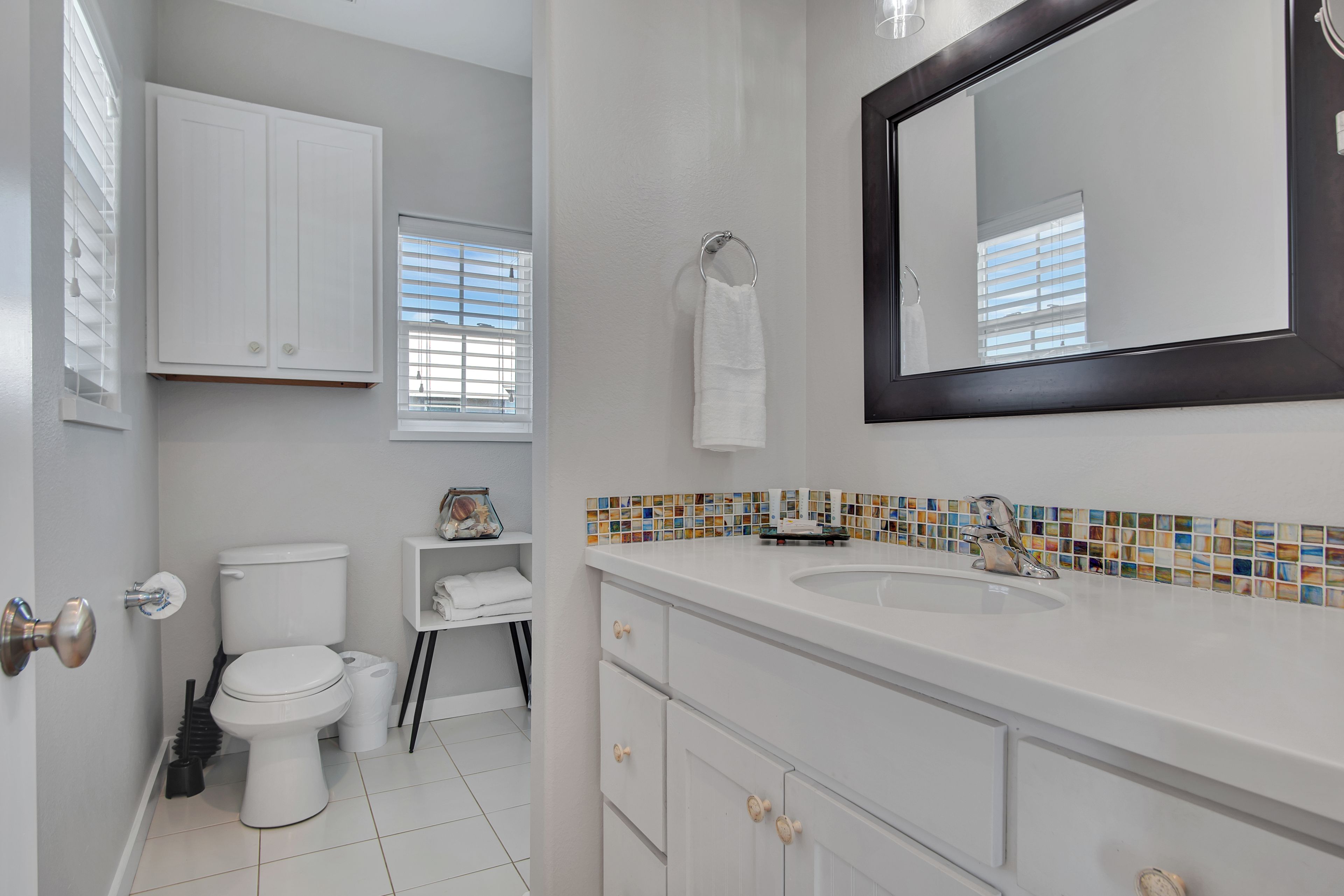 A bathroom with a toilet, sink, mirror, and towel rack.