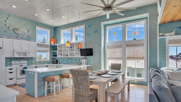 A spacious kitchen with a large island, white cabinetry, and a ceiling fan. - Nauti Beach by Silver Sands Vacation Rentals (Port Aransas)
