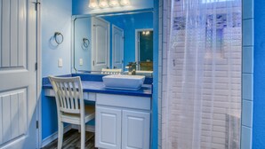 A bathroom with a blue and white color scheme, featuring a sink, mirror, and chair. - Moore Fun House by Silver Sands Vacation Rentals (Port Aransas)