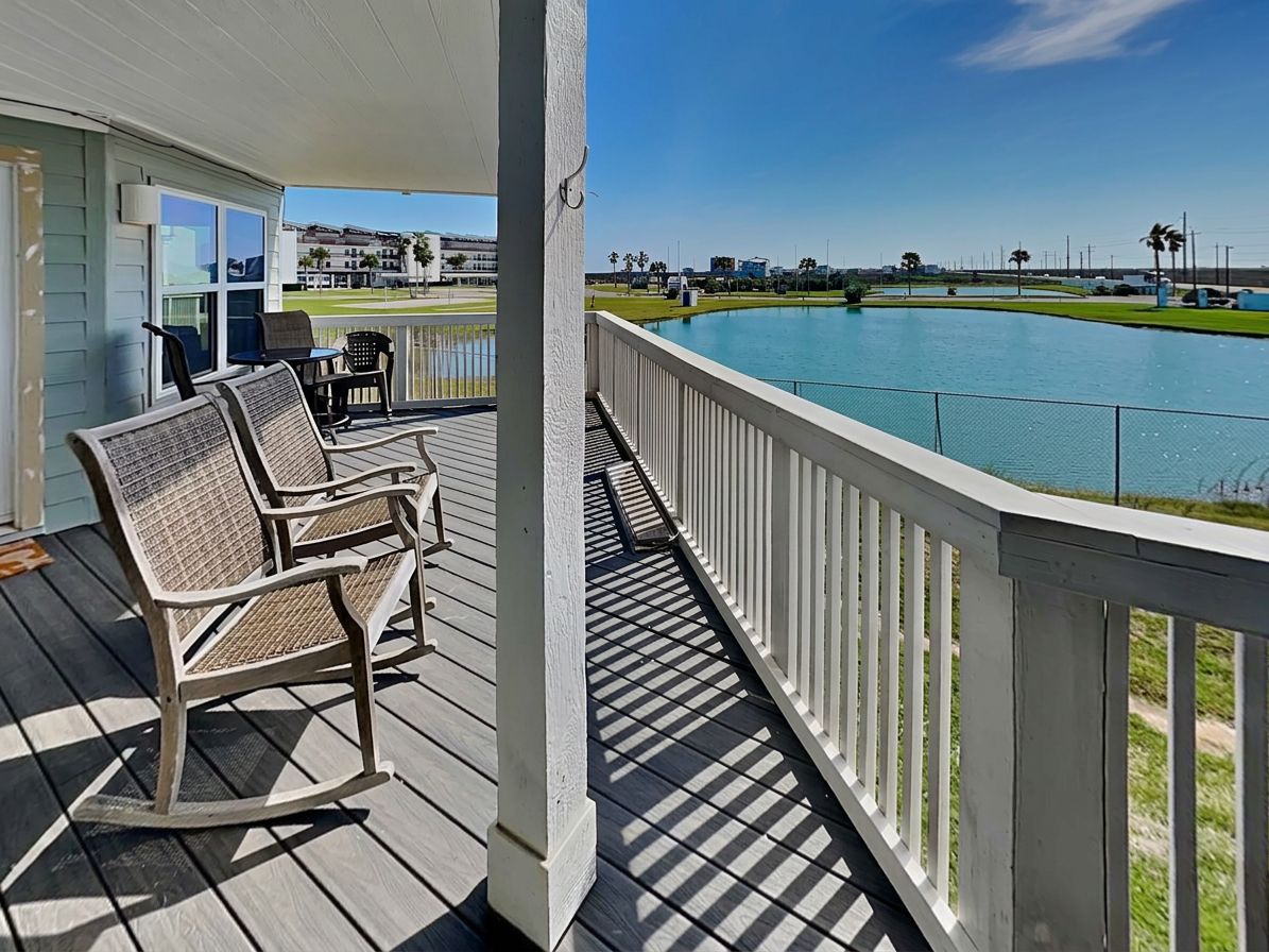 A wooden deck with outdoor furniture, a pool, and a view of a golf course.
