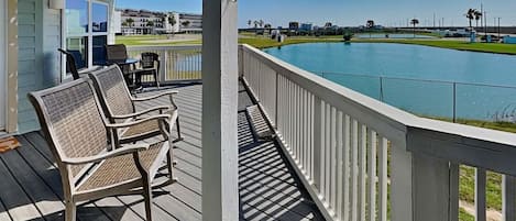 Eine Holzterrasse mit Gartenmöbeln, einem Pool und Blick auf einen Golfplatz.