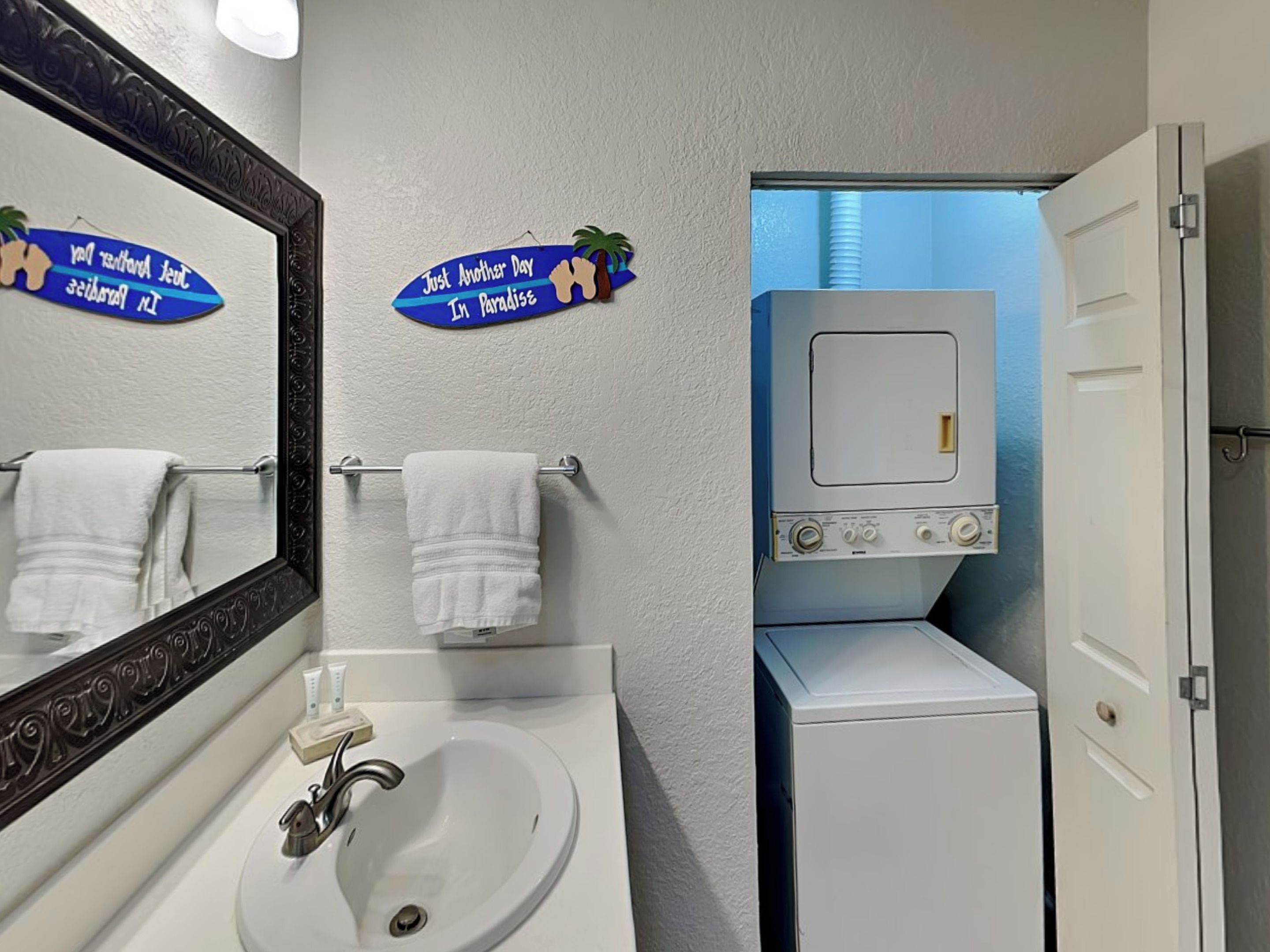 Une salle de bain équipée d’un lavabo, de deux serviettes, d’un miroir et d’un lave-linge.