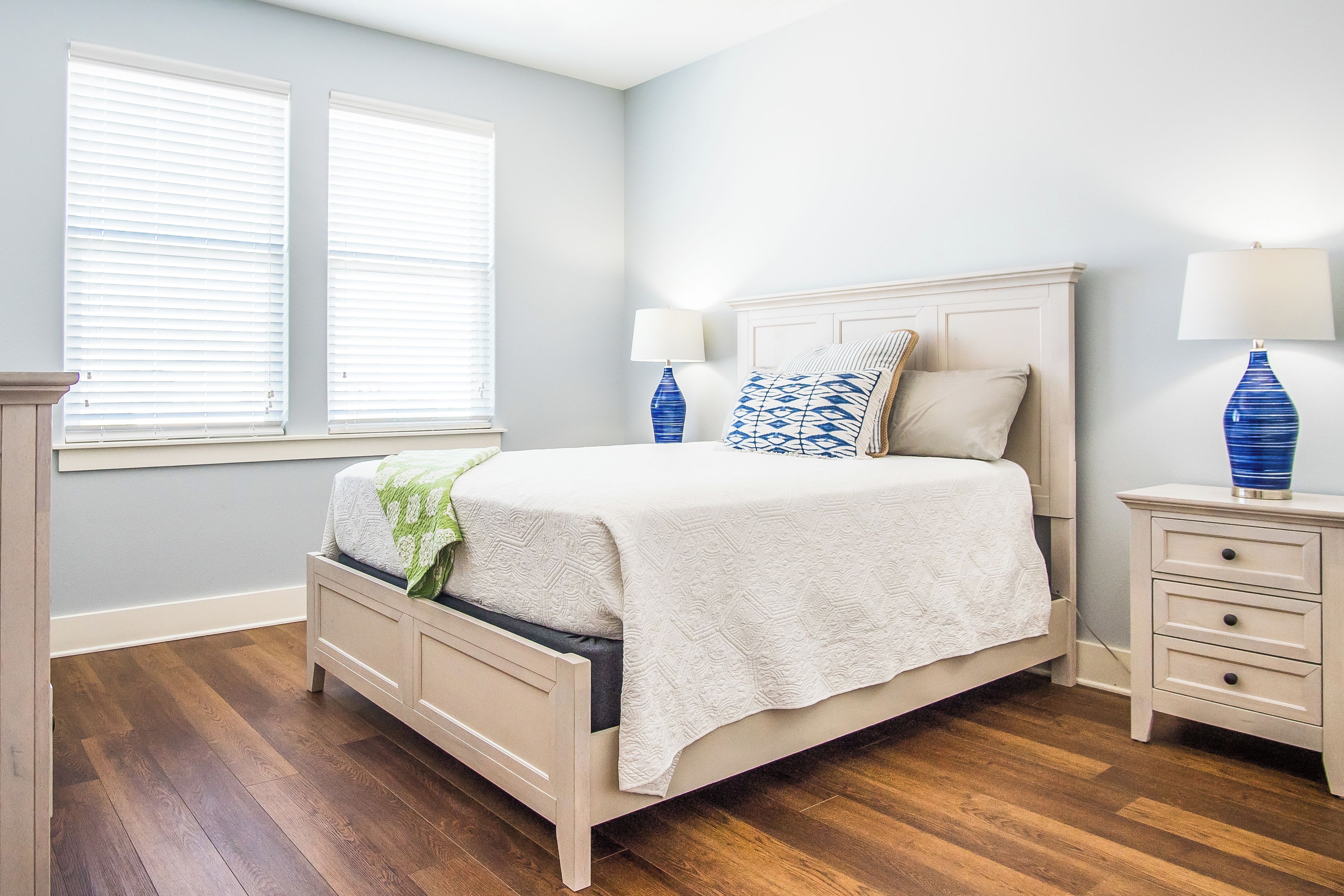 A bedroom with a bed, bedside tables, and a window with blinds.