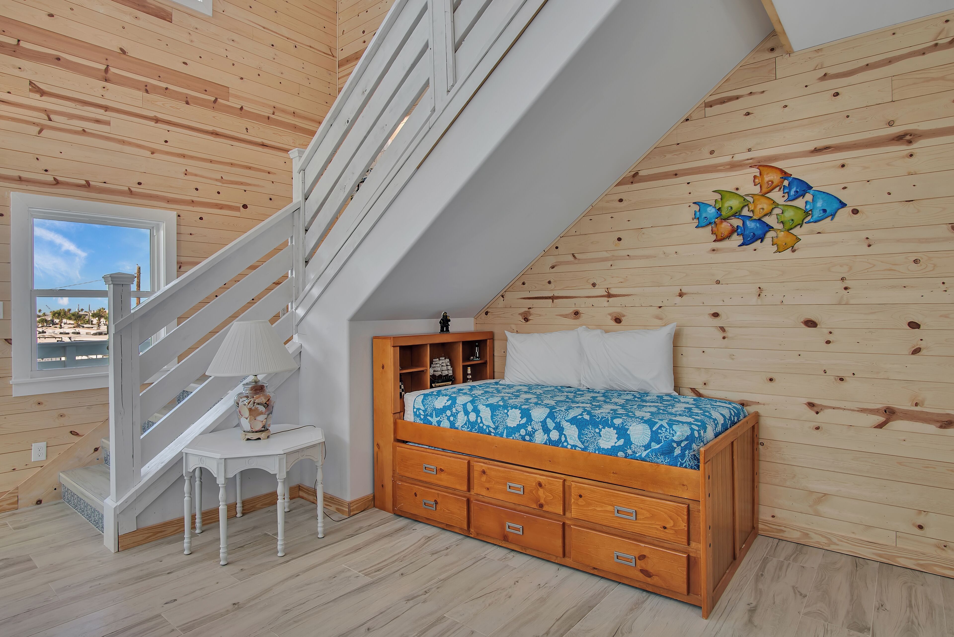 Un dormitorio con una cama de madera, una mesita de noche, una lámpara y una escalera.