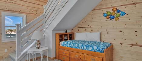 Un dormitorio con una cama de madera, una mesita de noche, una lámpara y una escalera.