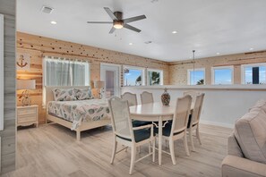 Une pièce spacieuse comprenant un lit, une table à manger avec des chaises et un ventilateur de plafond.