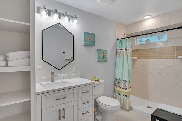 A bathroom with a white sink, a mirror, a toilet, and a shower curtain.