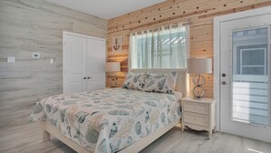 Une chambre à coucher avec un lit, des tables de chevet, une fenêtre avec des rideaux et une porte avec des stores.