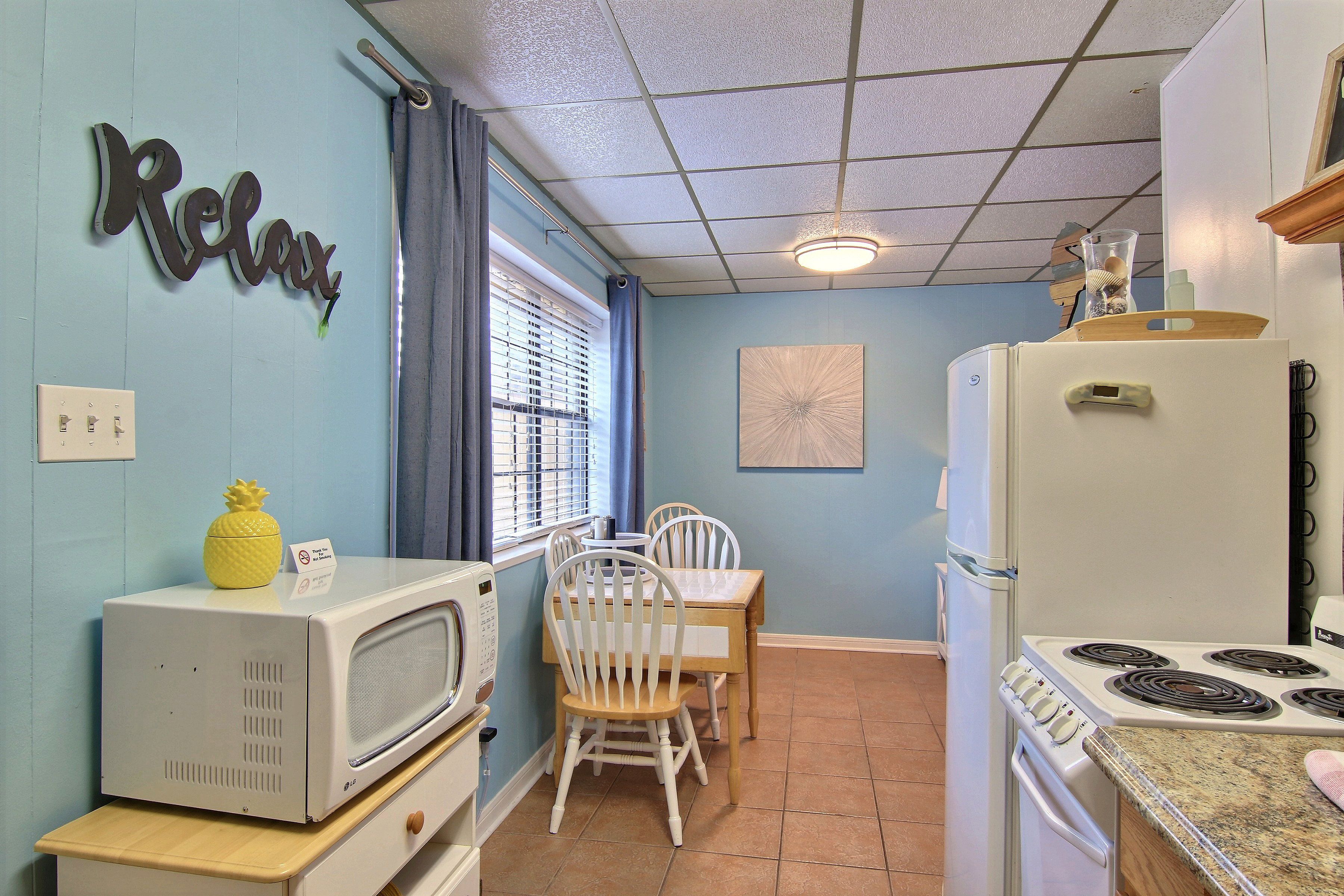A kitchen with a microwave, stove, and chairs.