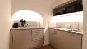 A compact kitchen with a microwave, coffee maker, and utensils on the counter. - Das Fischer Boardinghouse KF (Kaufbeuren)