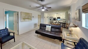 A spacious living room with a black leather sofa, two armchairs, a coffee table, and a dining area in the background. - Paradise Retreat by Silver Sands Vacation Rentals (Port Aransas)