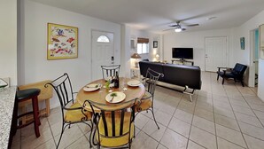 A dining area with a round table, chairs, and a bar area with a TV. - Paradise Retreat by Silver Sands Vacation Rentals (Port Aransas)