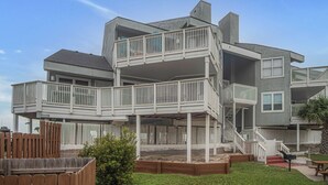 A multi-level residential building with a deck and outdoor seating area. - Pawsitively Paradise by Silver Sands Vacation Rentals (Port Aransas)