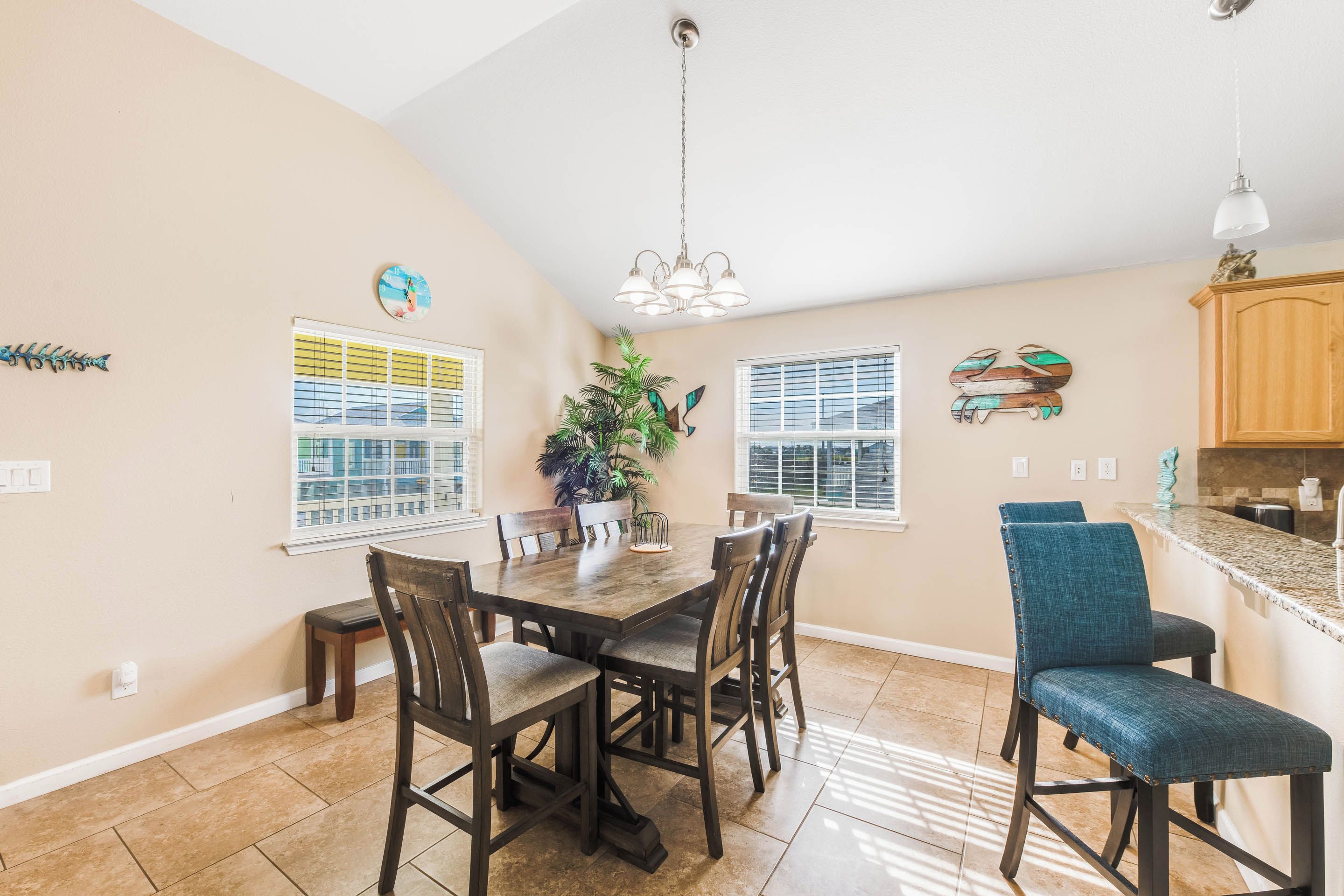 A dining area with a wooden table and chairs, a potted plant, and a kitchen counter with a sink.