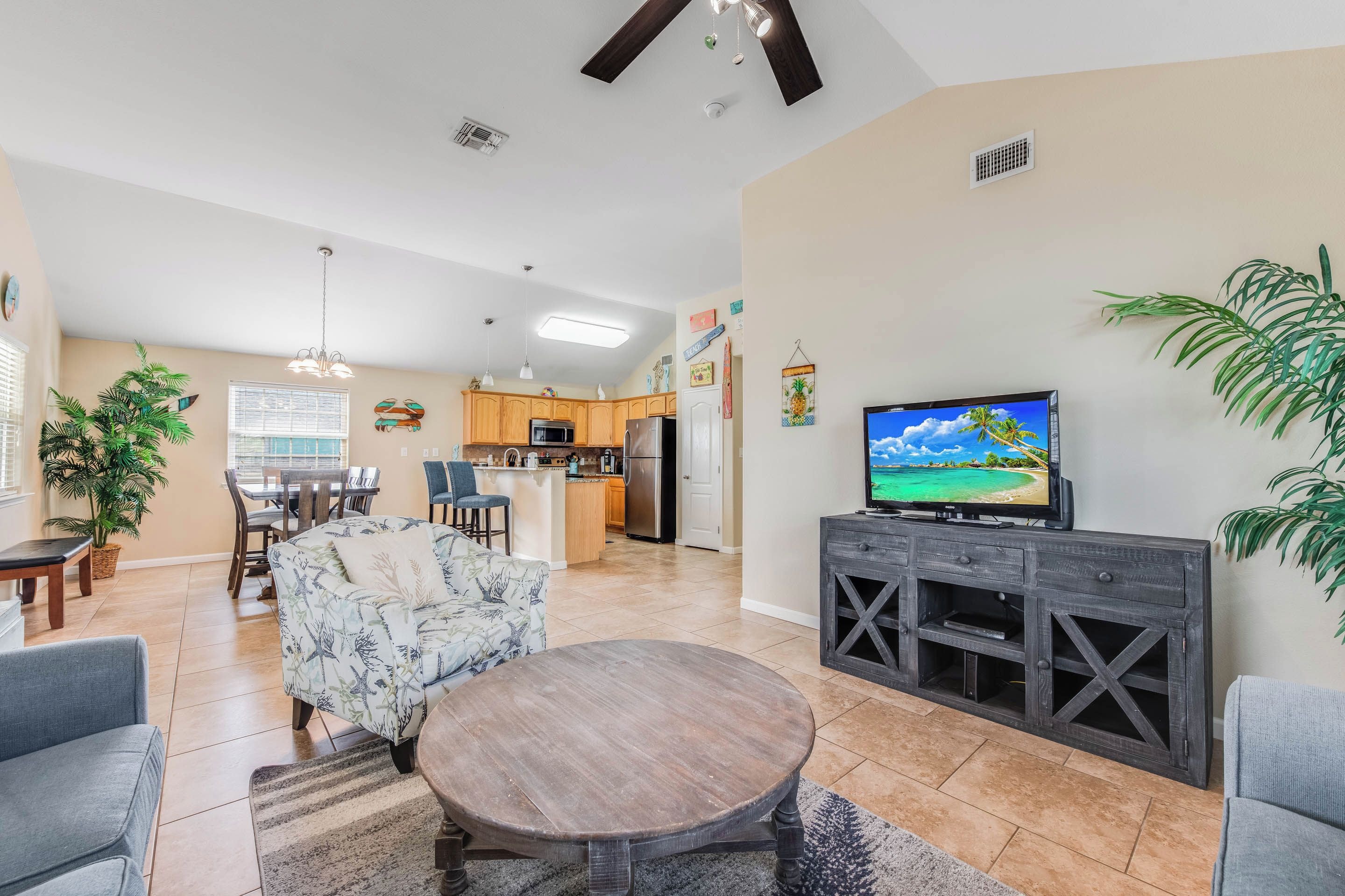 A spacious living room with a dining area, kitchen, and a TV on a wooden cabinet.
