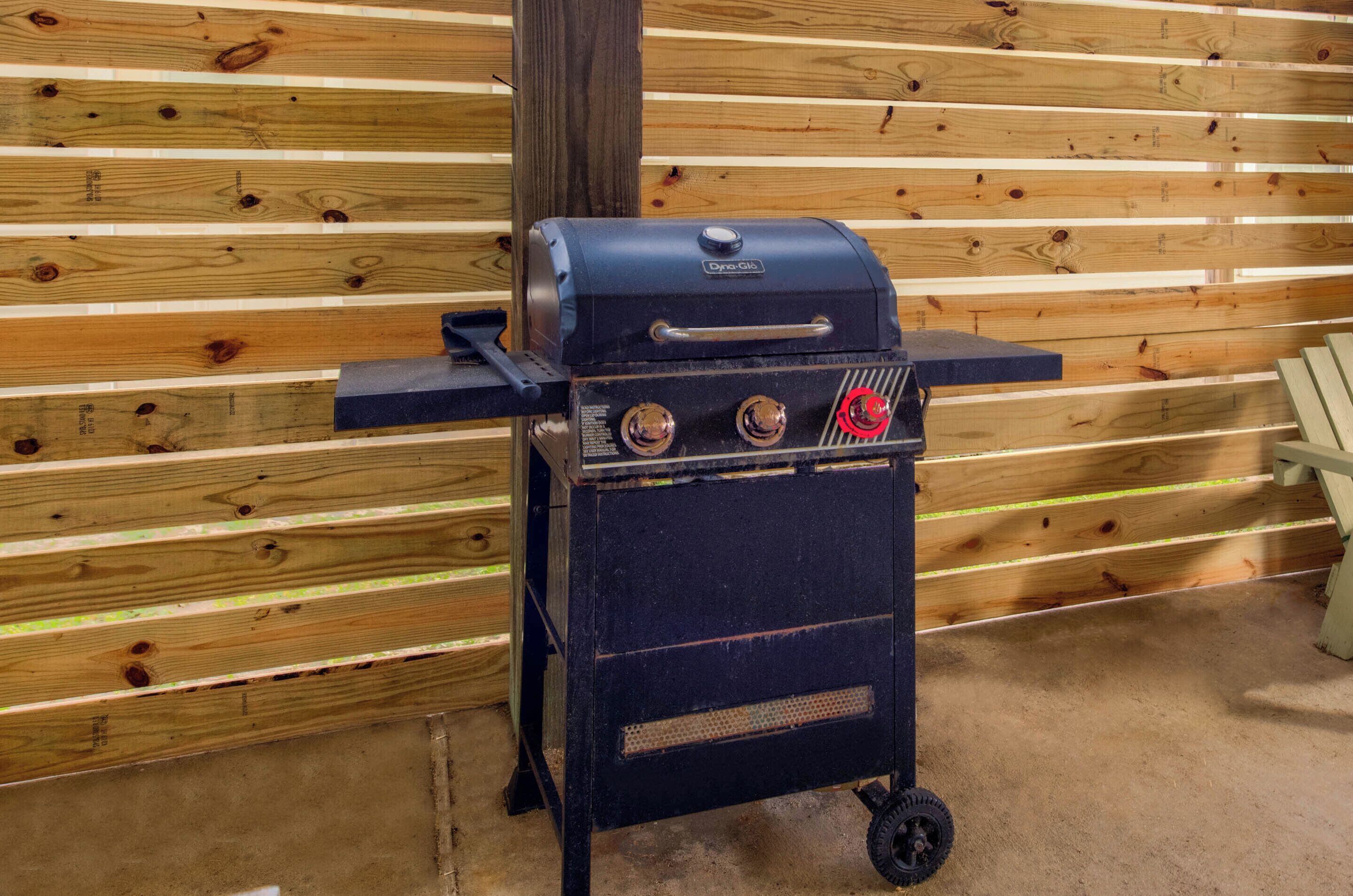 A portable grill with two control knobs and a digital display, set against a wooden wall.