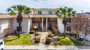 A two-story building with a central staircase, surrounded by palm trees and well-maintained lawns. - Pearl Marlin by Silver Sands Vacation Rentals (Port Aransas)