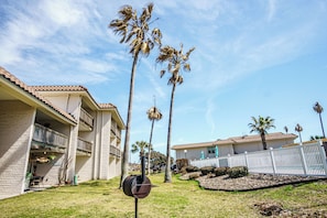 Un edificio residencial con fachada de ladrillo, varios balcones y un césped bien cuidado con palmeras.