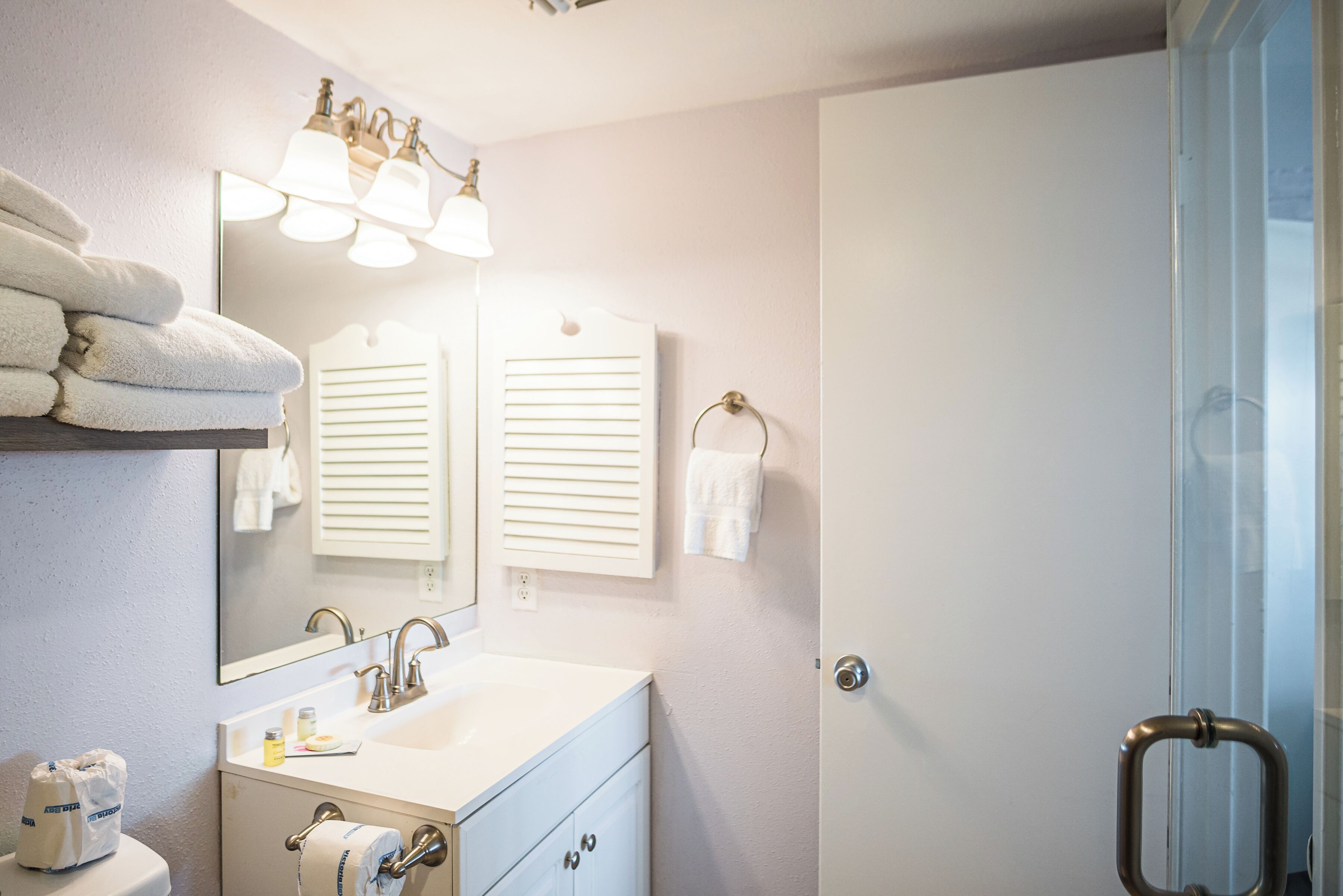 Une salle de bain équipée d’un lavabo, d’un miroir, d’un porte-serviettes et d’une porte de douche en verre.