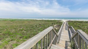 A wooden boardwalk leading to a beach with a clear view of the ocean. - Porpoise of Life by Silver Sands Vacation Rentals (Port Aransas)