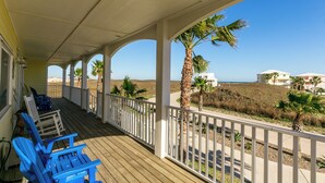 A covered porch with blue chairs and a view of the beach. - Porpoise of Life by Silver Sands Vacation Rentals (Port Aransas)