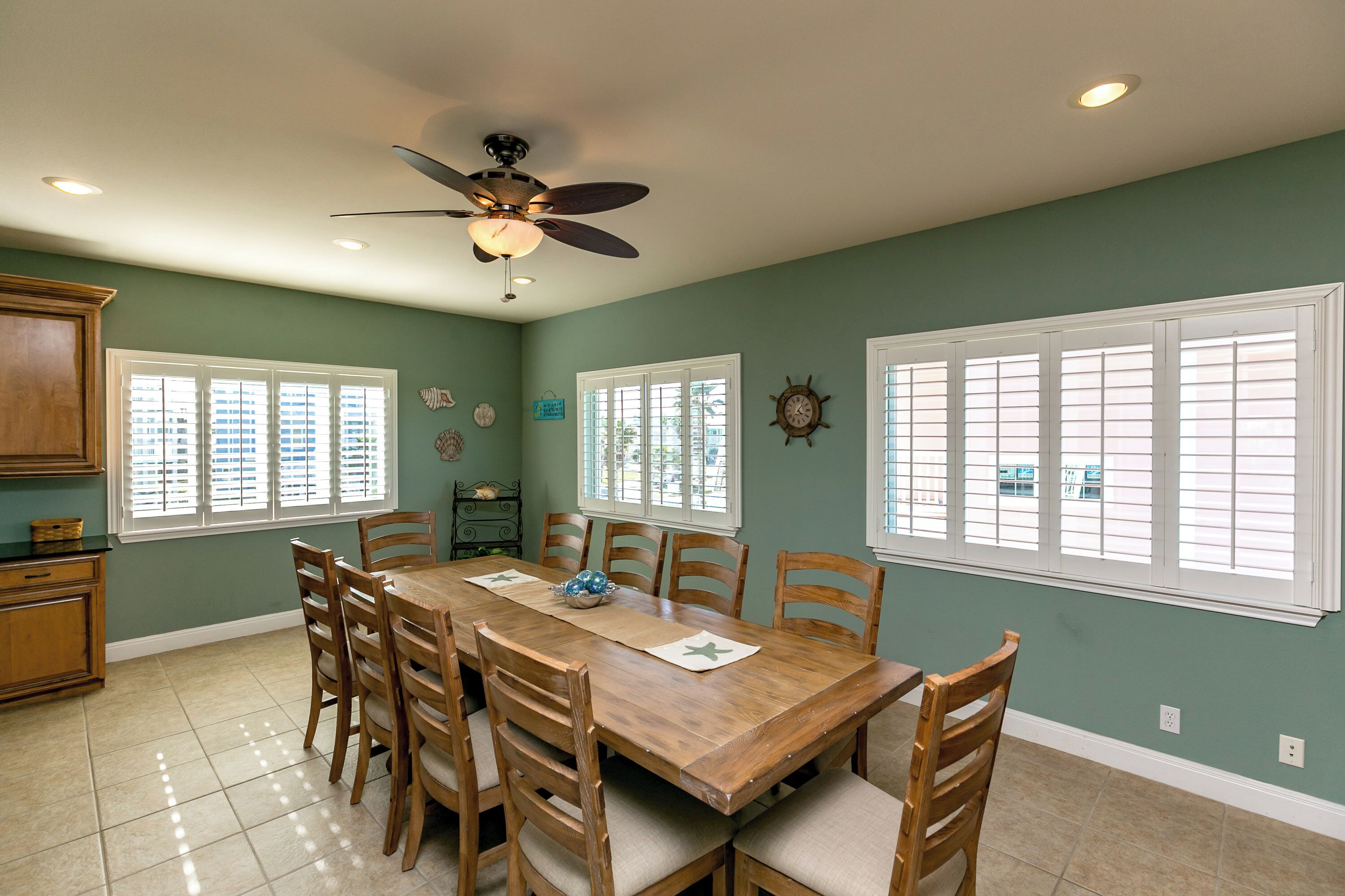 A dining room with a wooden table, chairs, and a ceiling fan.