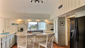 Eine Küche mit Barbereich, weißen Schränken, einem schwarzen Kühlschrank und einem Fenster mit Ausblick.