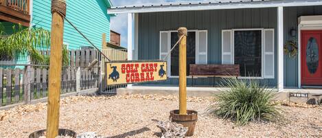 Un edificio rústico con un cartel que dice "GOLF CART CORRAL" y una valla de madera.