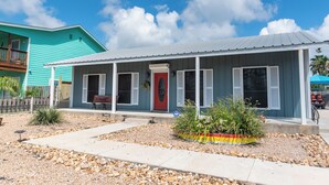 A two-story house with a red door, a covered porch, and a gravel driveway. - Port A Ponderosa by Silver Sands Vacation Rentals (Port Aransas)