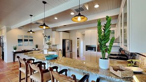 A spacious kitchen with a large island, bar stools, and pendant lighting.