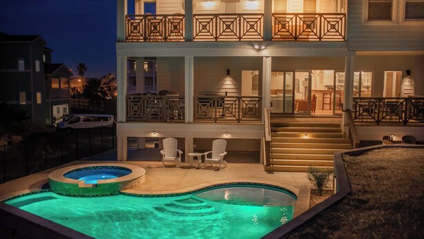 A two-story house with a swimming pool, outdoor seating, and a staircase leading to the upper level.