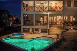 Une maison à deux étages dotée d’une piscine, d’un espace salon extérieur et d’un escalier menant à l’étage supérieur.