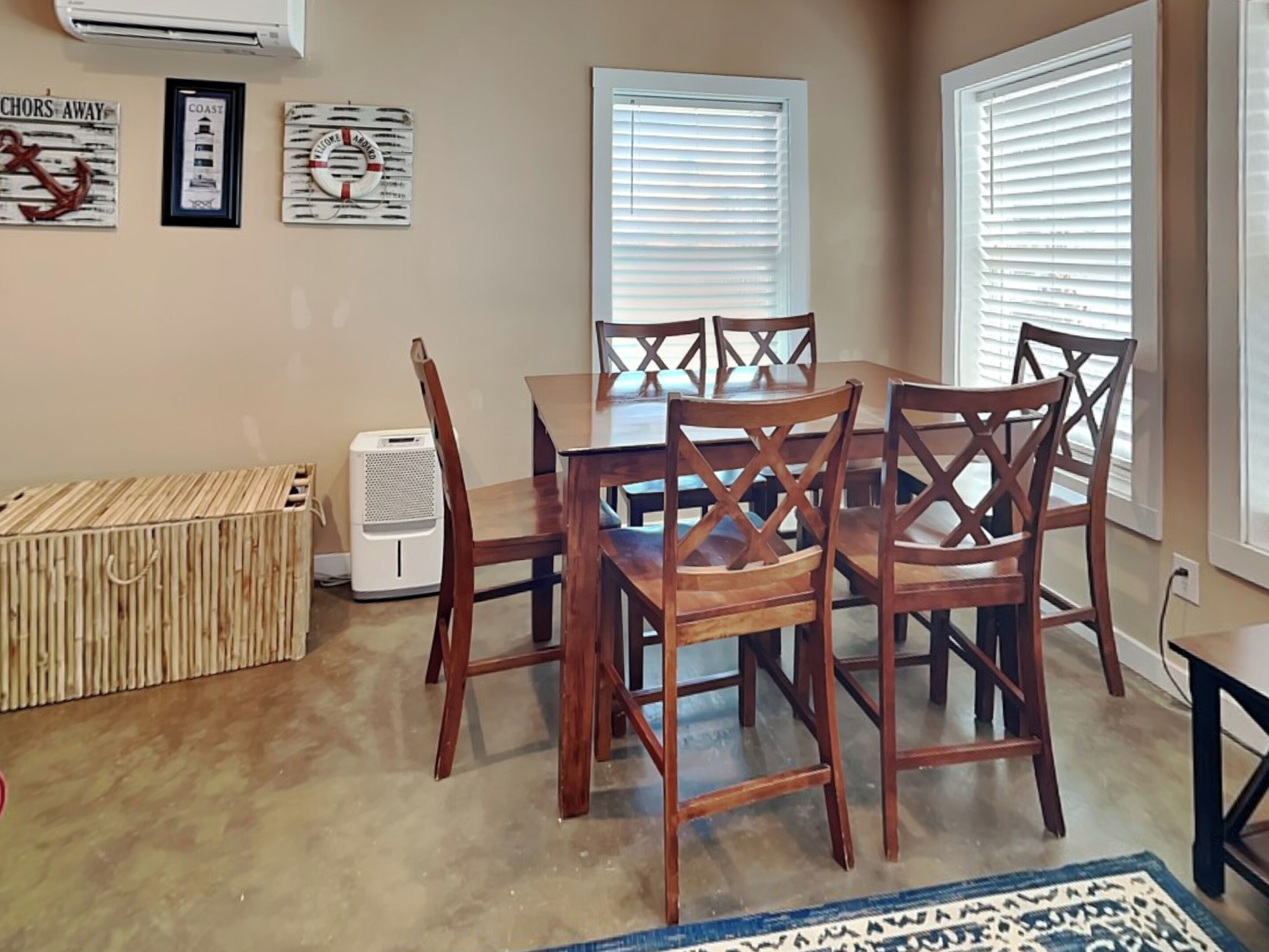 A dining area with a wooden table and chairs, air conditioning unit, and decorative wall art.