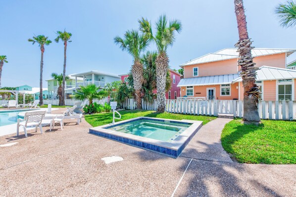 Zona de piscina con sillones de descanso, un jacuzzi y palmeras.