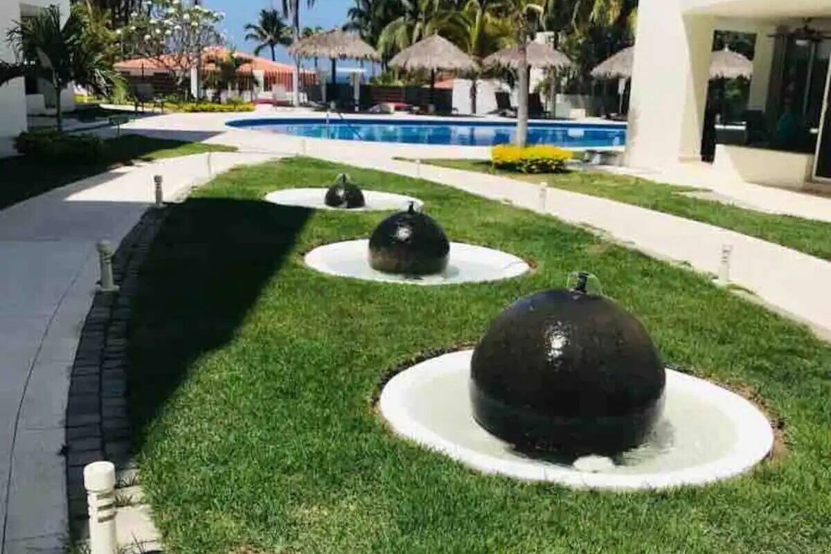Ein Innenhof mit Pool, Palmen und einer Fontäne.