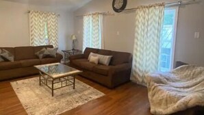 Ein geräumiges Wohnzimmer mit zwei Sofas, einem Couchtisch und einem Deckenventilator.