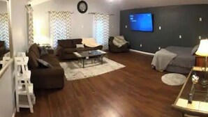 Ein Wohnzimmer mit einer Couch, Sesseln, einem Couchtisch und einem Fernseher.