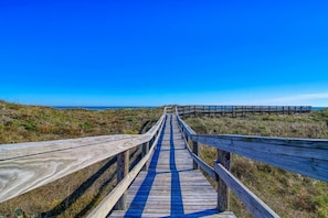 A wooden boardwalk leading to the beach with a clear blue sky.